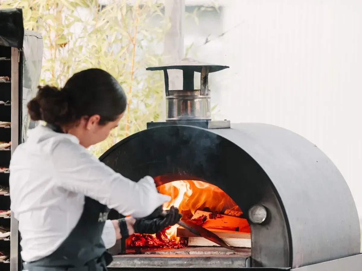 Een pizzabakker bij de houtoven