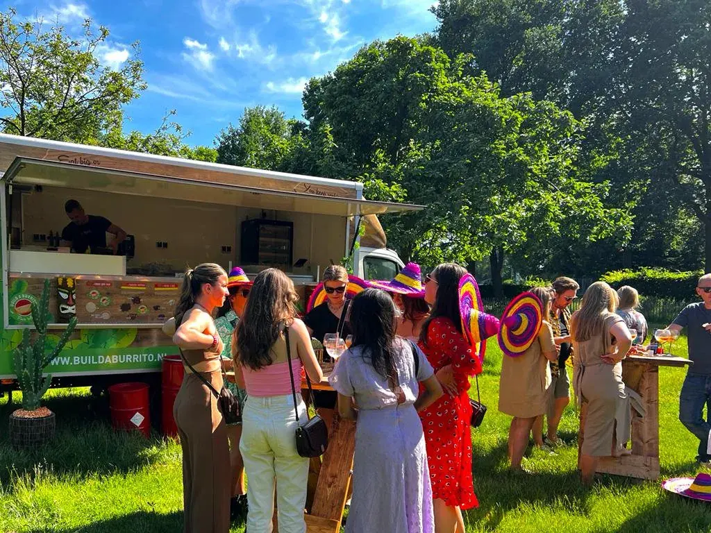 De foodtruck van Build a Burrito met gasten in een tuin, te huur via Feestkarhuren.nl