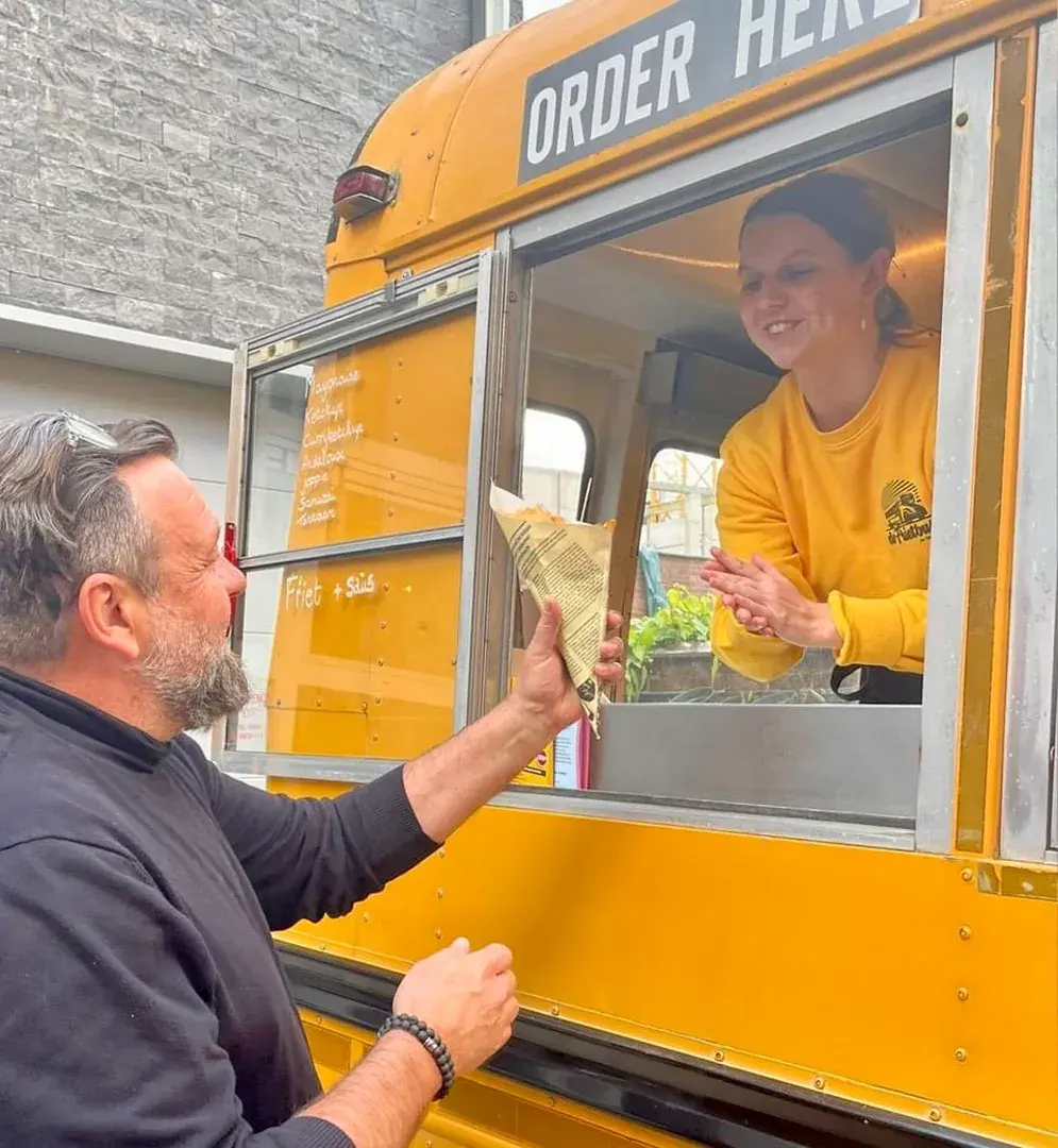 Frietjes worden uitgedeeld aan het loket van De Frietbus