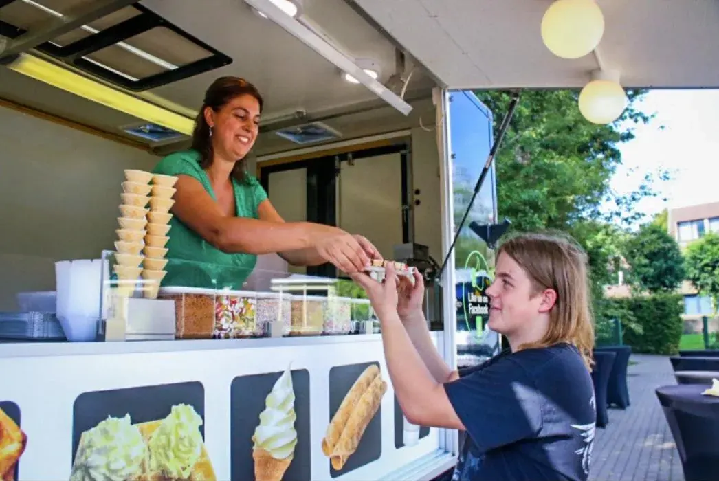Een wafel wordt aan een gast gegeven bij De Wafelwagen