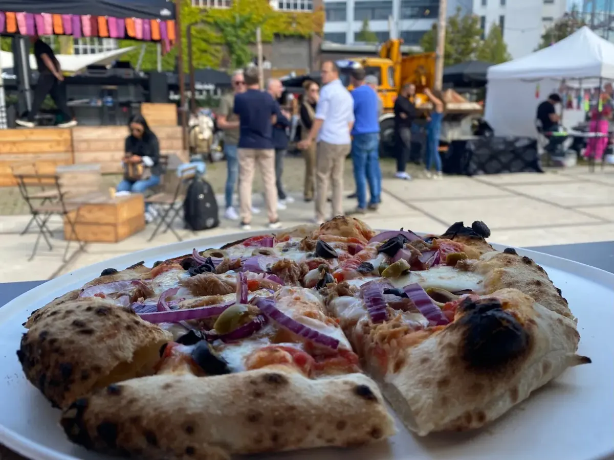 Een verse pizza met gasten op de achtergrond