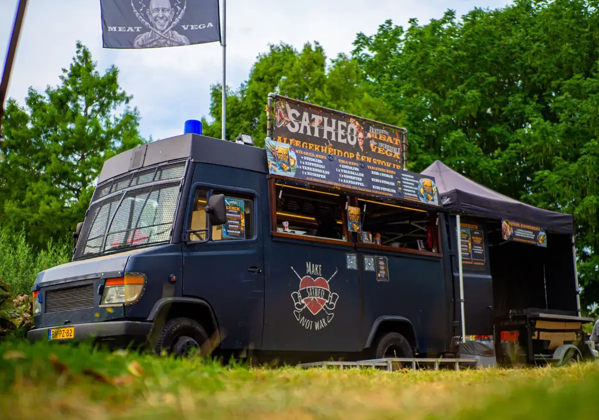 De ME-bus van Satheo op een grasveld, te huur via Feestkarhuren.nl