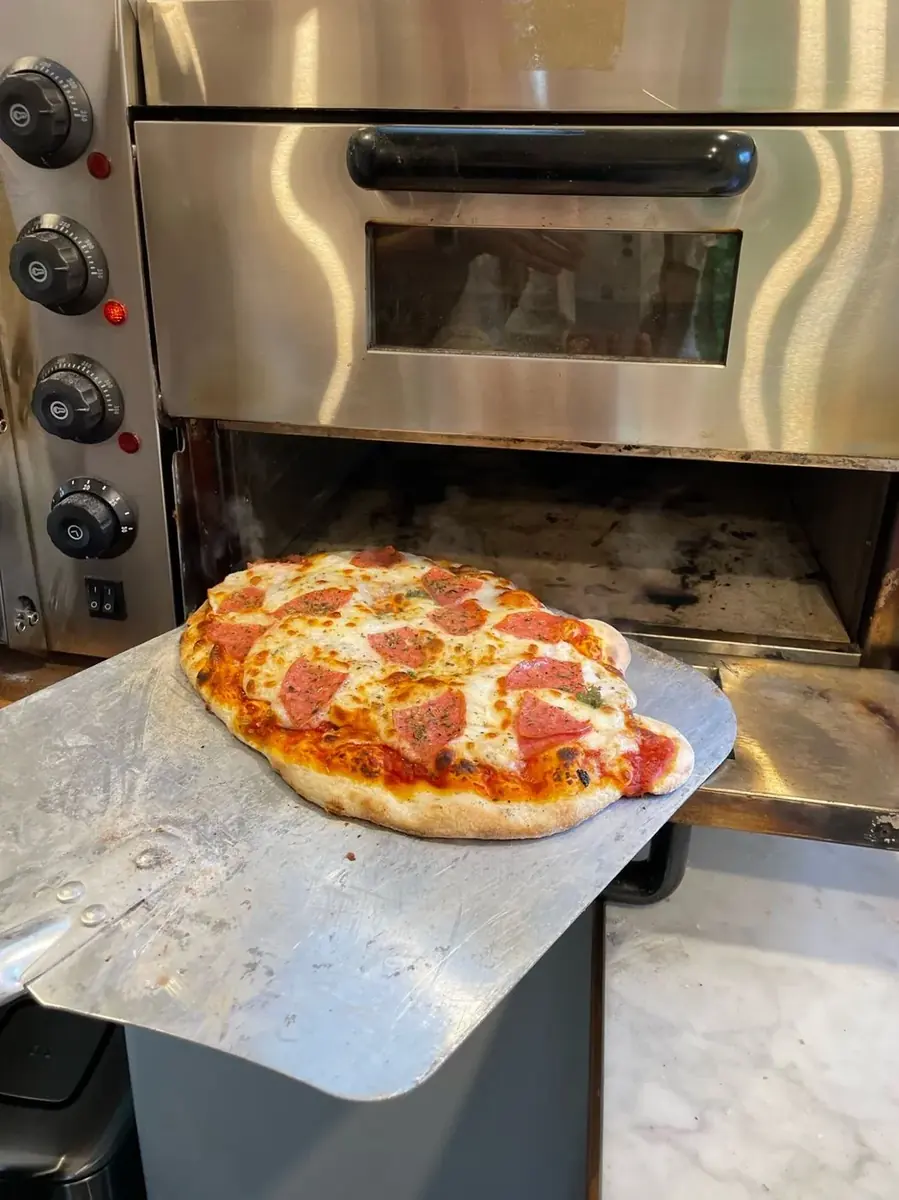 Een pizza komt uit de oven bij Tasty Truck