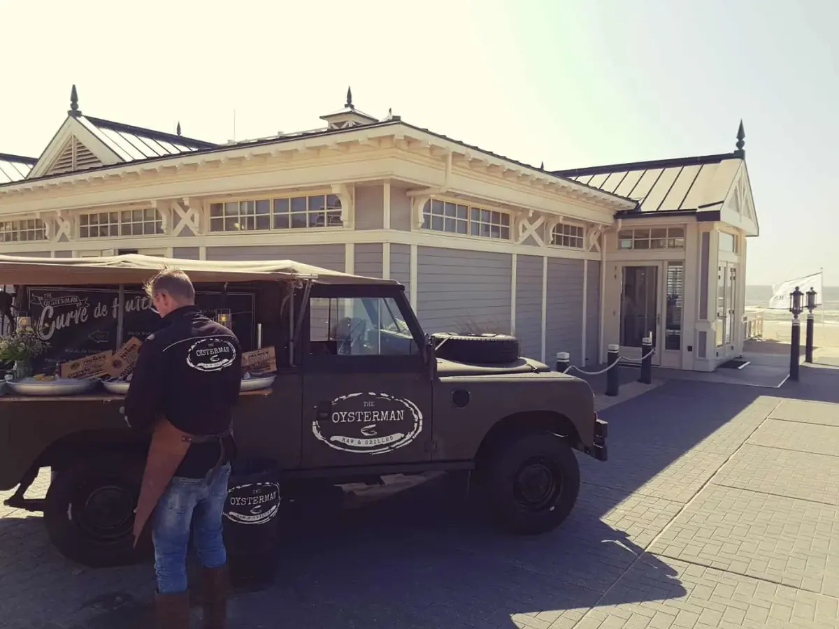De Land Rover bij een paviljoen aan zee
