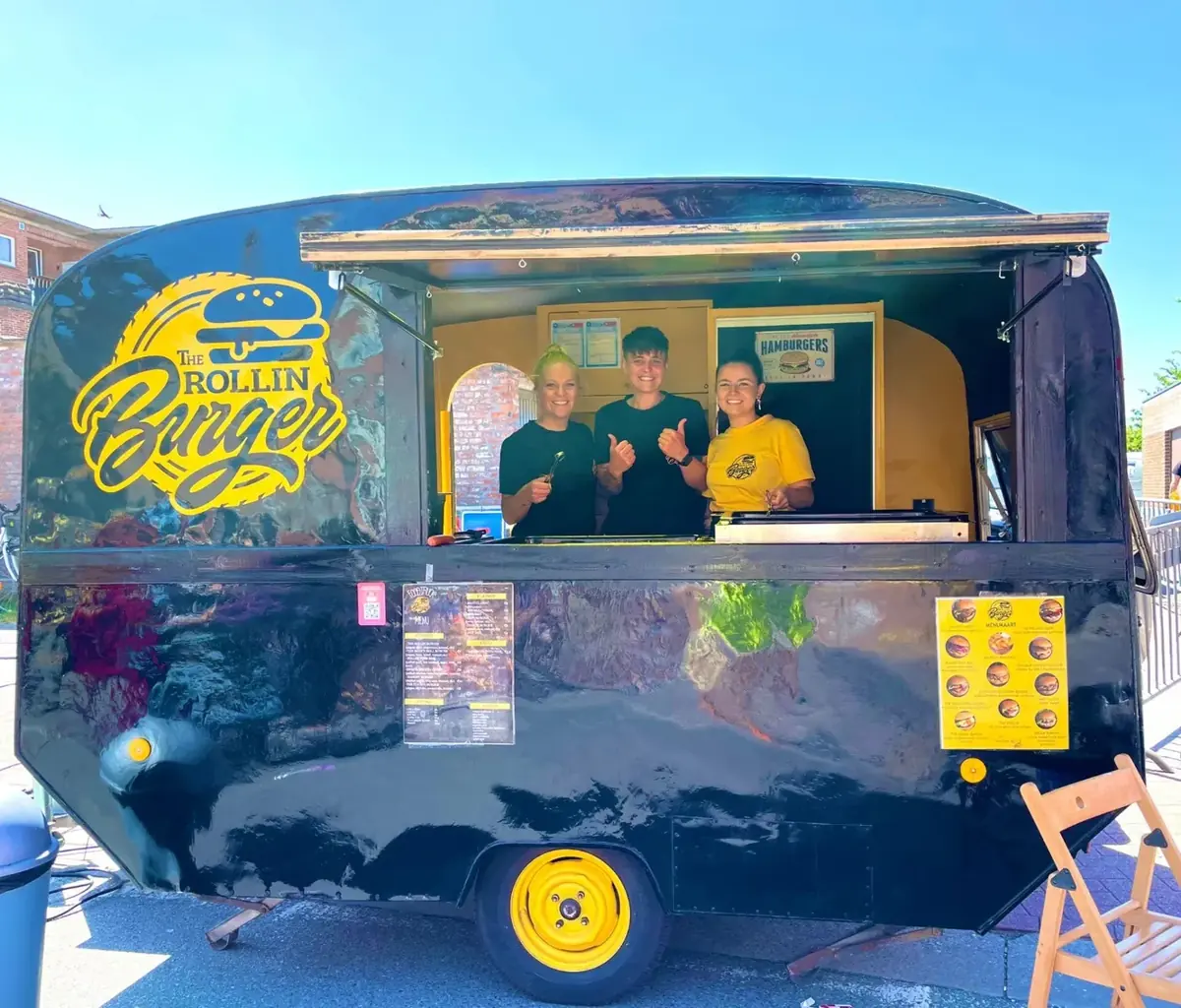 De foodtruck van The Rollin'Burger met het team achter het loket, te huur via Feestkarhuren.nl