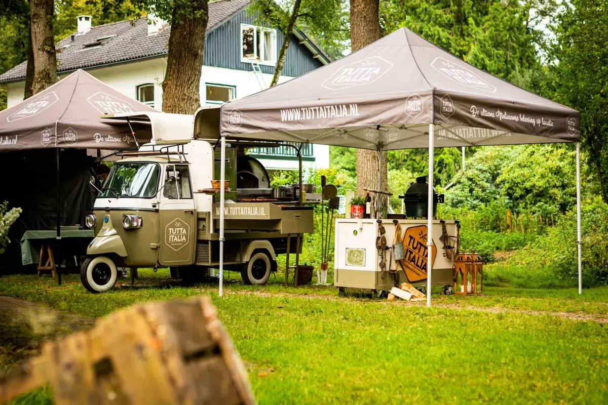 De foodtruck van Tutta Italia tussen de tenten op een tuinfeest, te huur via Feestkarhuren.nl