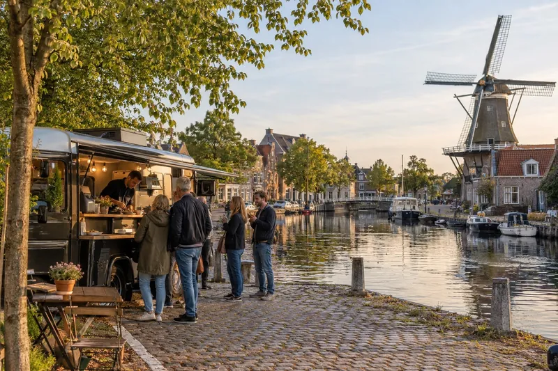 Poffertjeskraam bij grachtje en molen in een klein Fries stadje, Friesland
