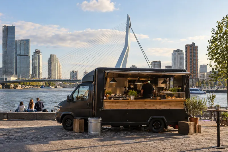 Hamburgertruck aan de Maas met de Erasmusbrug en de skyline van Rotterdam